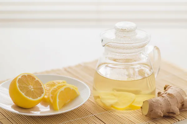 Segelas infused water jahe lemon segar dengan potongan jahe dan irisan lemon, minuman sehat untuk detoks tubuh