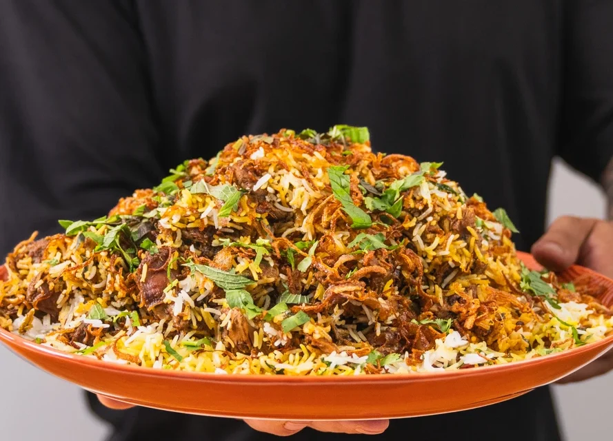 A steaming plate of Hyderabadi Biryani garnished with fresh herbs